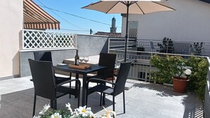 Un balcon avec une table, des chaises, un parasol et des plantes en pot.