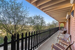 Un balcon doté d’une balustrade en bois, d’un espace salon extérieur et offrant une vue sur les arbres et le paysage.