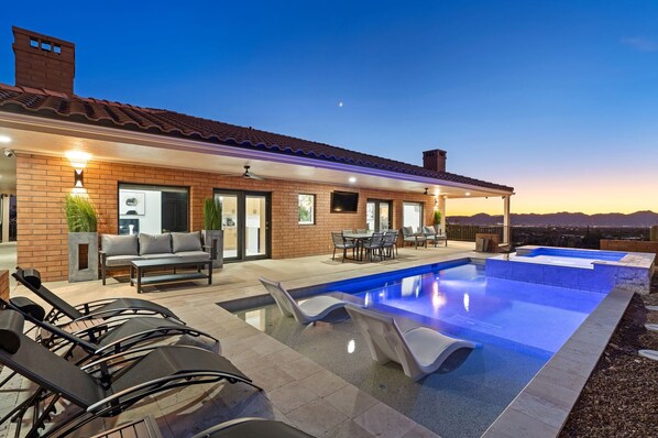 A modern outdoor pool area with a patio, lounge chairs, and a dining set.