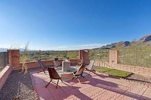 Un patio al aire libre con un brasero, asientos y vistas a montañas.