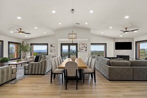 Un vaste espace de vie comprenant une table à manger, des canapés et un téléviseur fixé au mur.