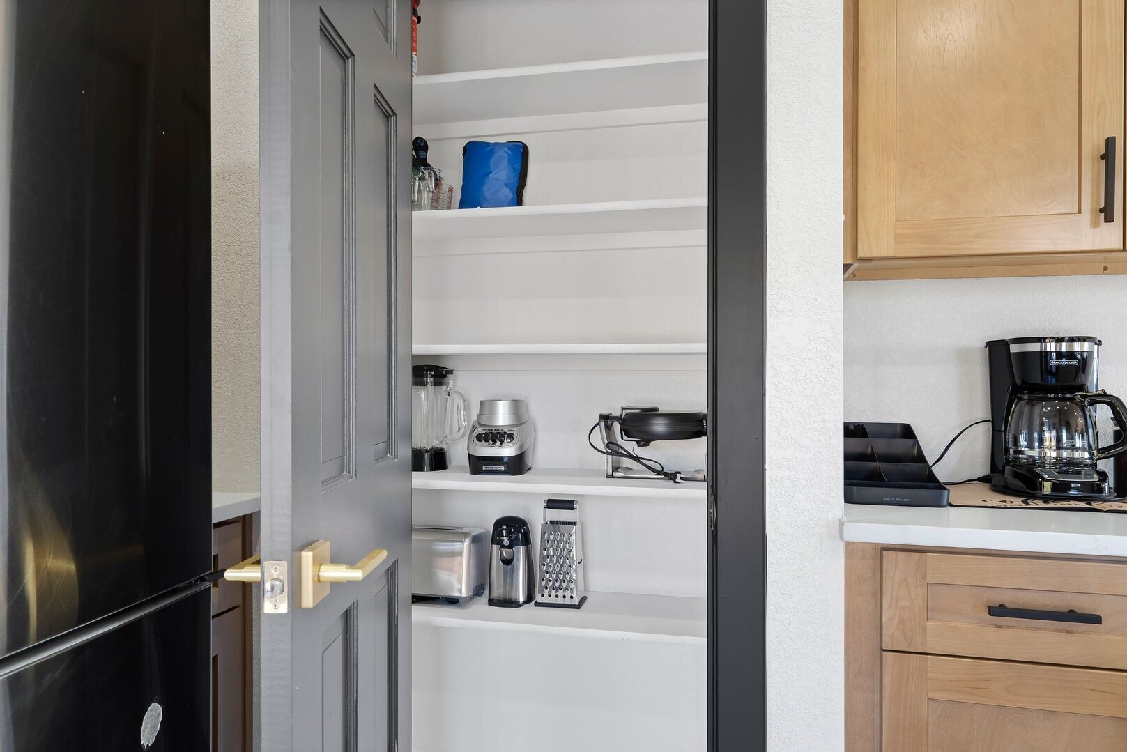 Una cocina con nevera, cafetera y microondas en la encimera.