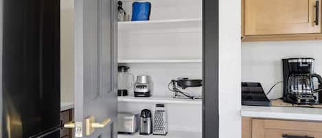 Una cocina con nevera, cafetera y microondas en la encimera.