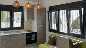 Eine moderne Küche mit einem grünen Sofa, großen Fenstern und Pendelleuchten.
