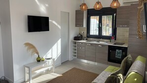 Eine moderne Küche mit Einbauofen, Spüle und Fenster. Eine weiße Sitzbank mit Vase und Fernbedienung.