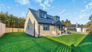 A residential house with a sloped roof, a brick exterior, and a well-maintained lawn. - The Bunker - UK47763 (Bamburgh)