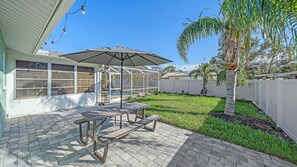 A patio with a table and chairs, a covered seating area, and a pool.