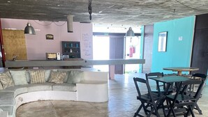 A spacious living area with a curved sofa, a dining table with chairs, and a kitchen area in the background. - Pousada Américas (Guarujá)