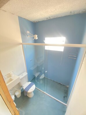 A small bathroom with a toilet, sink, and shower stall.
