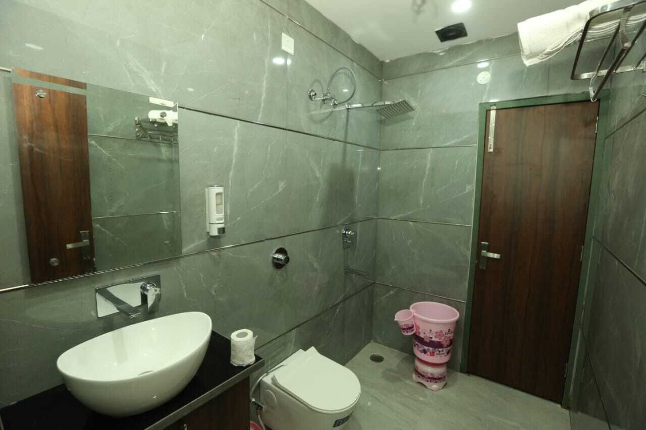 A modern bathroom with a large mirror, a white sink, a toilet, and a shower.