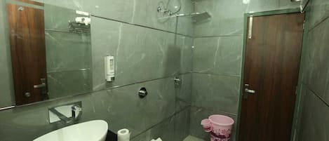 A modern bathroom with a large mirror, a white sink, a toilet, and a shower.