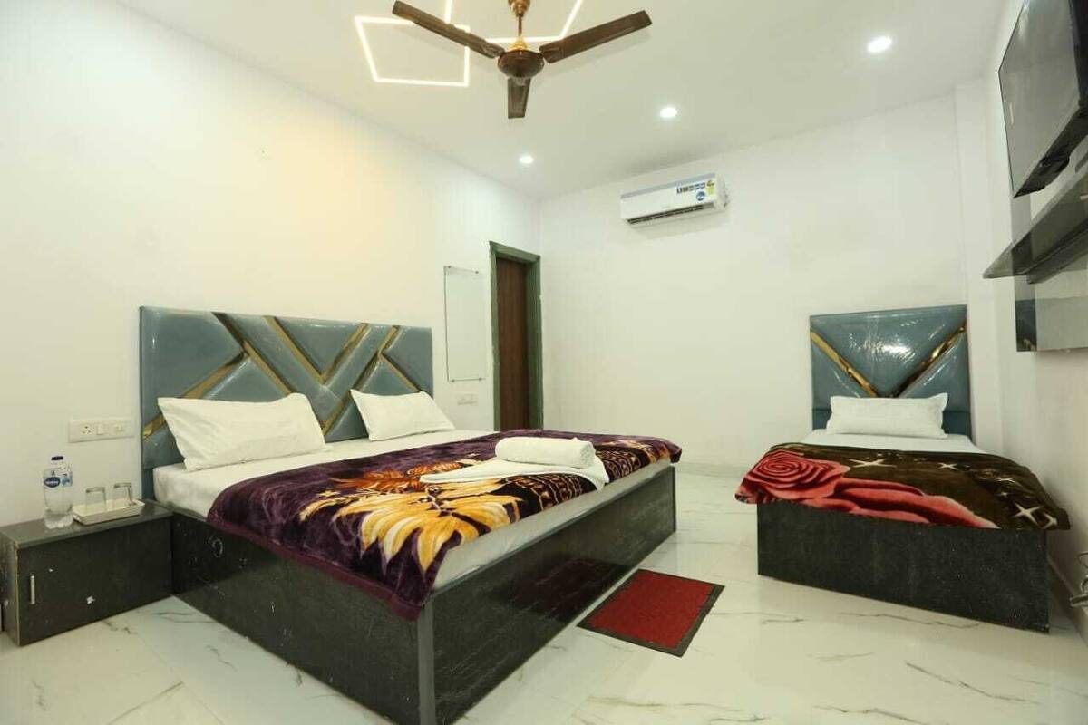 Habitación de hotel con dos camas, ventilador de techo, aire acondicionado y piso de mármol.
