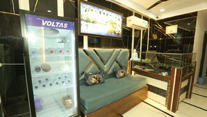 Un moderno vestíbulo de hotel con una zona de estar, un minibar y una pantalla de televisión que muestra un paisaje urbano.