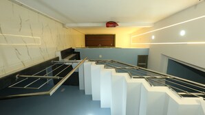 Una escalera moderna con barandilla de metal, pared de mármol y piso azul.