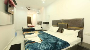 Habitación de hotel con una cama grande, un escritorio, una silla, un armario, un espejo y un ventilador de techo.