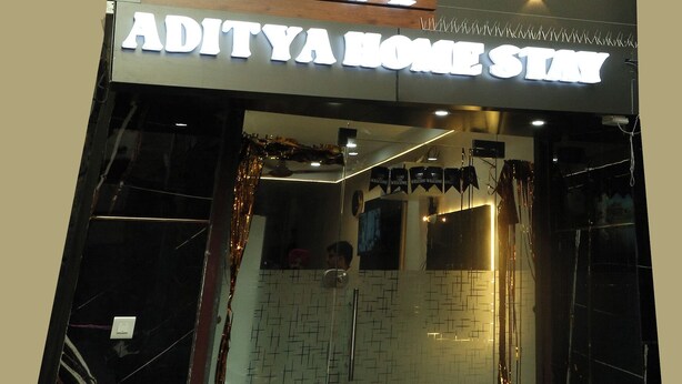 Un edificio moderno con un cartel que dice 'ADITYA HOME STAY'.
