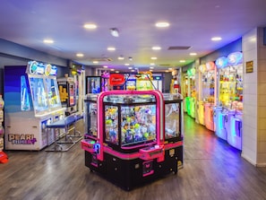 Eine Indoor-Spielhalle mit Krabpspielen und einem 'Pearl Fishery'-Spiel.
