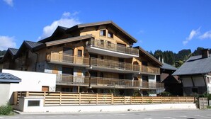 A multi-story building with balconies, likely a hotel or resort, with a clear blue sky in the background.