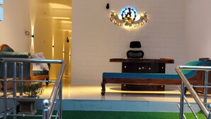 A modern interior with a staircase leading to a seating area, a decorative wall piece, and a ceiling fan. - Srikrishna Paradise (Tiruvannamalai)