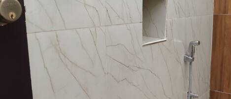 A bathroom with a marble wall, a shower, and a toilet.