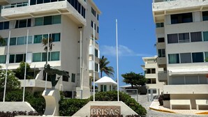 A modern building with a sign reading "BRISAS" in front. - 1BD Apartment with pool and beach access (Cancún)
