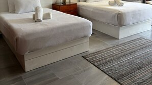 A hotel room with two beds, a nightstand with a lamp, a large window, and a ceiling fan. - 1BD Apartment with pool and beach access (Cancún)