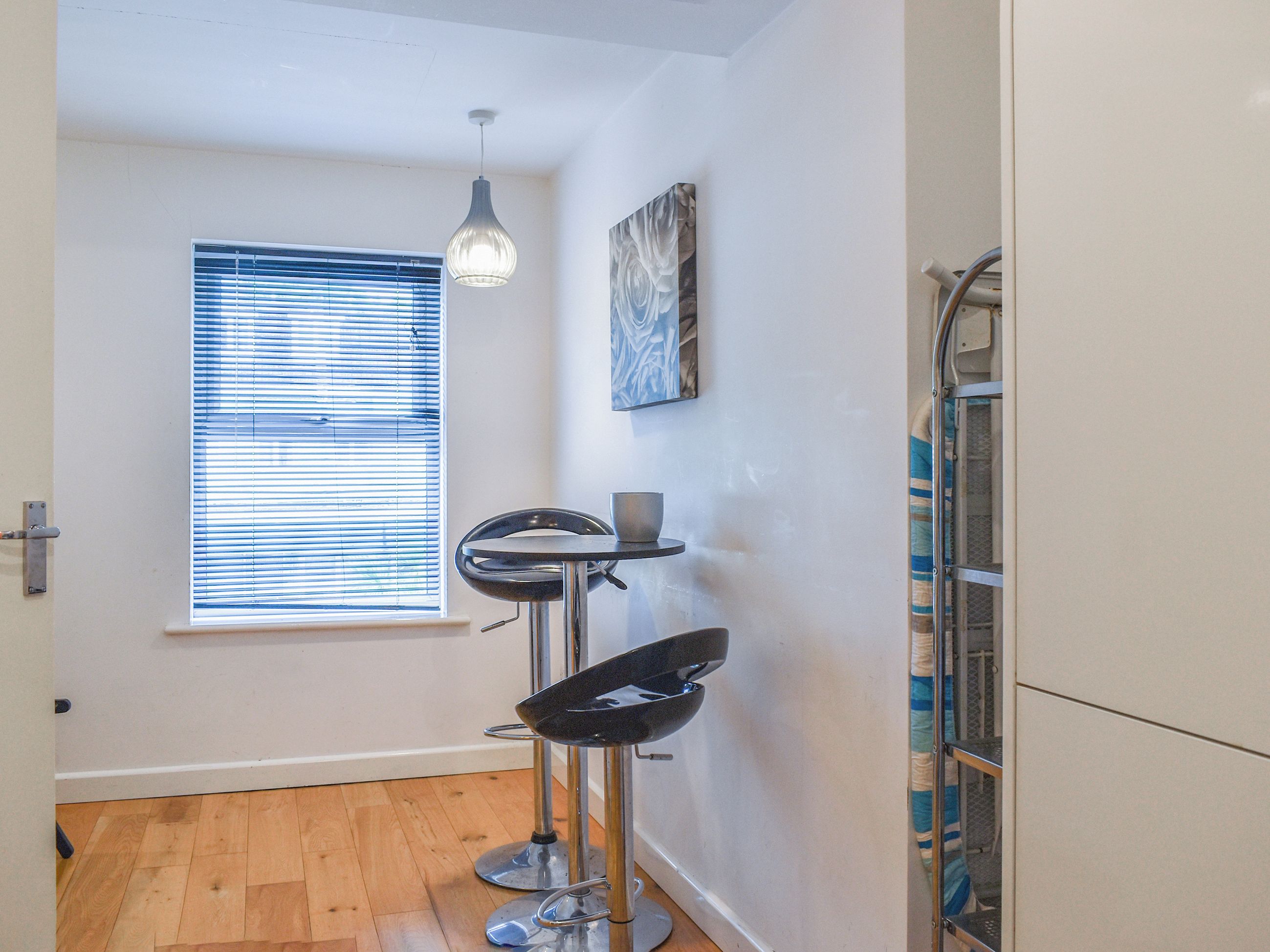 A small kitchen with a window, a sink, and a stool.