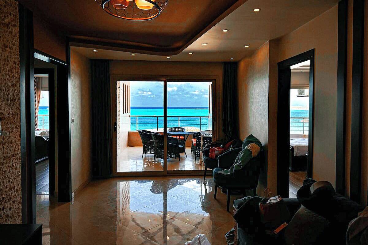 A spacious room with a large sliding glass door leading to a balcony with a view of the ocean.
