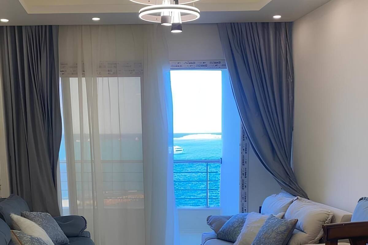 A spacious living room with two sofas, a coffee table, and a view of the ocean through a large window.