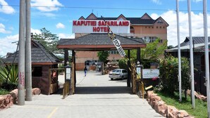 De ingang van Kaputiei Safariland Hotel, met een heldere lucht en een bord waarop de naam van het hotel staat.