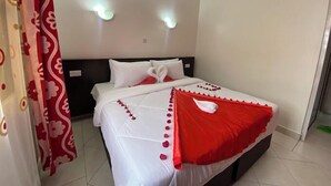 Een hotelkamer met een bed, witte gordijnen en een rood-witte spreideken.