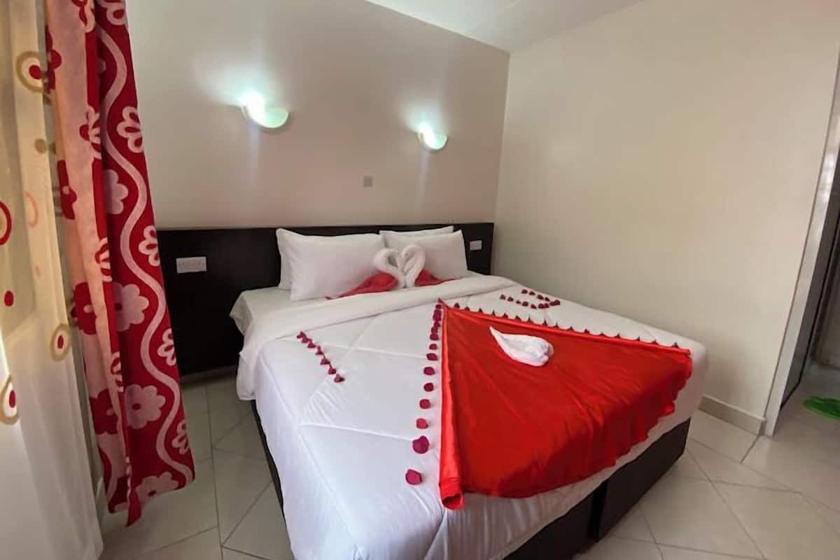 Een hotelkamer met een bed, witte gordijnen en een rood-witte spreideken.