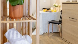 A wooden shelf with a potted plant and folded towels.