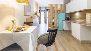 Una cucina moderna con un frigorifero color acquamarina, un tavolo da pranzo con prodotti per la colazione e una parete divisoria in legno.