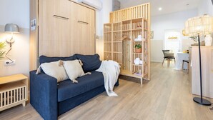 Un soggiorno moderno con un divano blu scuro, un armadio in legno e una scaffalatura di legno.