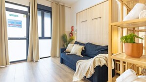 Una stanza con un divano blu scuro, un armadio in legno e uno scaffale con asciugamani e una pianta.