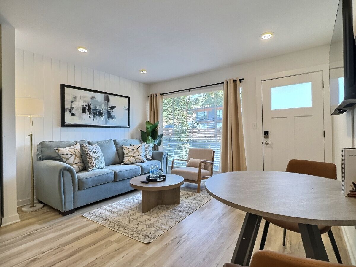 A modern living room with a sofa, armchair, coffee table, and a dining table.