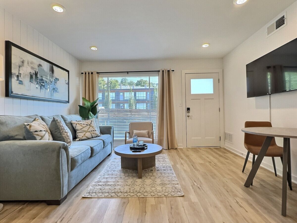 A modern living room with a sofa, coffee table, and a TV mounted on the wall.