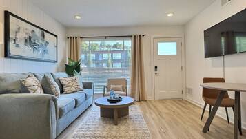 A modern living room with a sofa, coffee table, and a TV mounted on the wall.