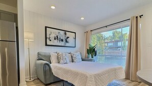 Ein Schlafzimmer mit einem Bett, einem Sofa, einer Lampe und einem Fenster mit Vorhängen.