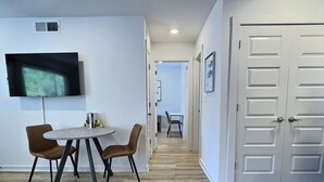 Ein modernes Interieur mit Essbereich, einem an der Wand befestigten Fernseher und einem Flur zu einem weiteren Zimmer.