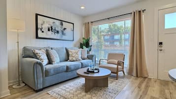 A modern living room with a light blue sofa, a round coffee table, and a beige armchair.