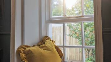 A window seat with a cushion, a glass of wine, and books.