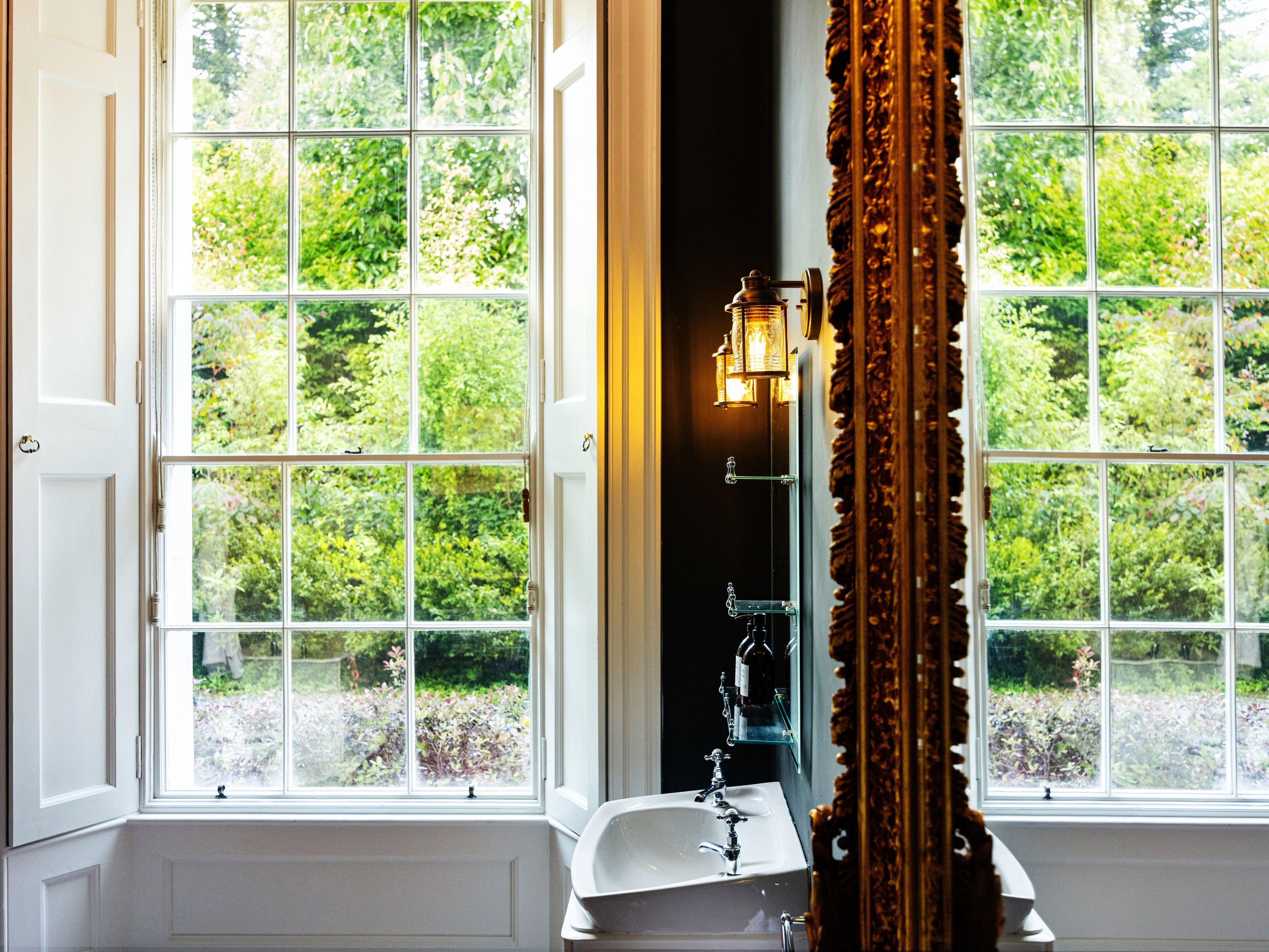 A bathroom with a large window, a sink, and a mirror.