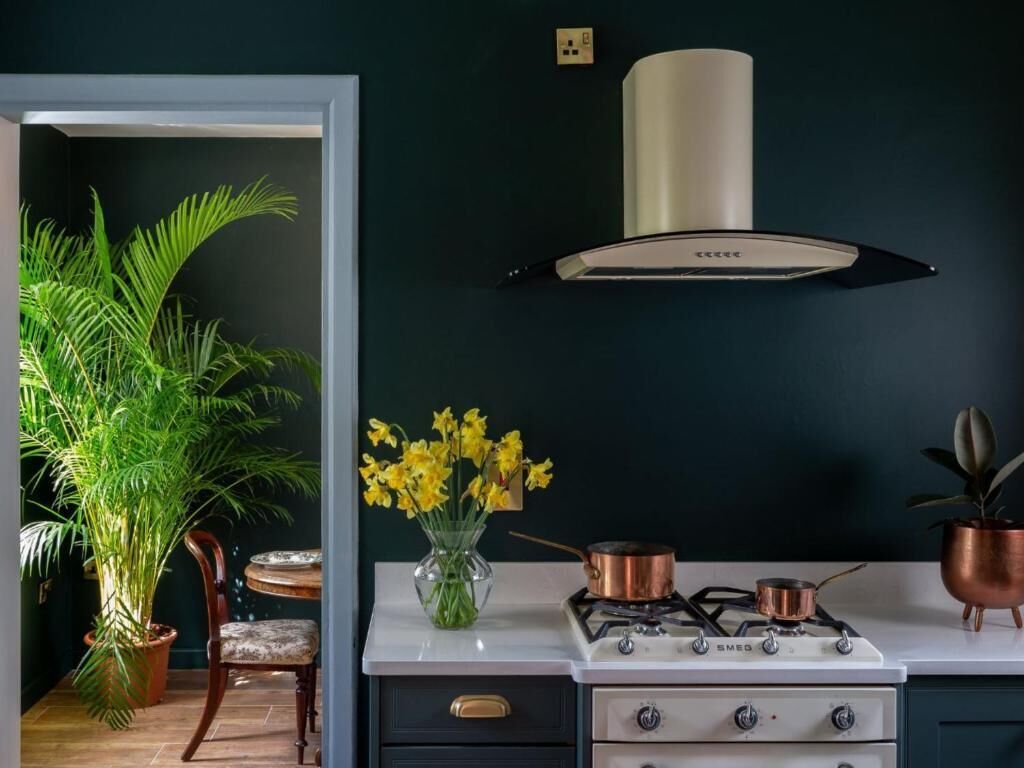 A kitchen with a white stove, copper pots, and a modern range hood.