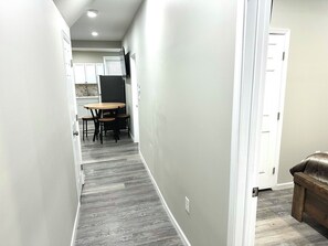 Enter a serene hallway leading to a dining area with a round table and flat-screen TV.