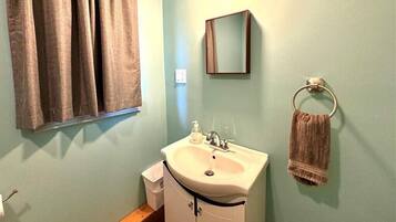 A bathroom with a sink, mirror, towel rack, and window with curtains.