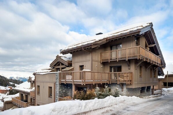Un immeuble en bois à plusieurs étages, doté de balcons, et entouré de neige.
