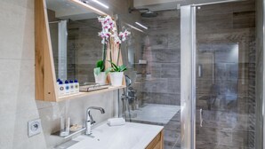 A modern bathroom with a glass shower enclosure, a large mirror, and a vanity with a sink and countertop. - Wifi, 150m from resort center, 3rd floor, sauna, balcony, parking, tv, 64m², Courchevel (Courchevel)