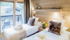 A hotel room with two beds, a wooden wall, a balcony with a chair, and a nightstand with a vase of flowers. - Wifi, 150m from resort center, 3rd floor, sauna, balcony, parking, tv, 64m², Courchevel (Courchevel)